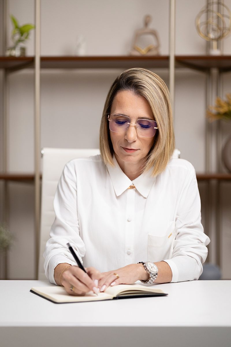 Keila Navarro escrevendo em um caderno em seu escritório, em atendimento atento